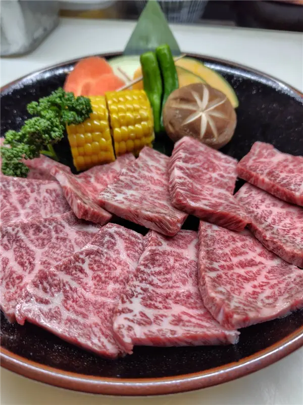 夕暮れ時の焼肉店の外観、入口へ続く通路と暖かな店内の光